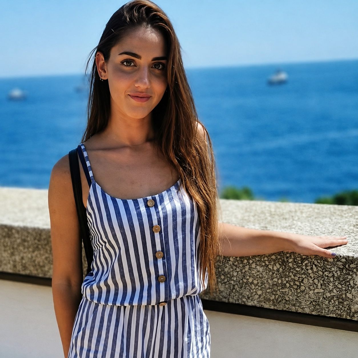 Foto di Eleonora Delnevo appoggiata a un muretto, con il mare sullo sfondo